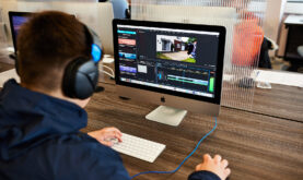 Boston College Media Student working at a laptop with headphones on