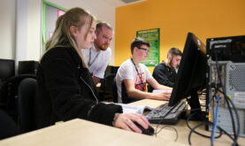 Two Boston College Accounting Student studying at desktop computers, with a lecturer supporting