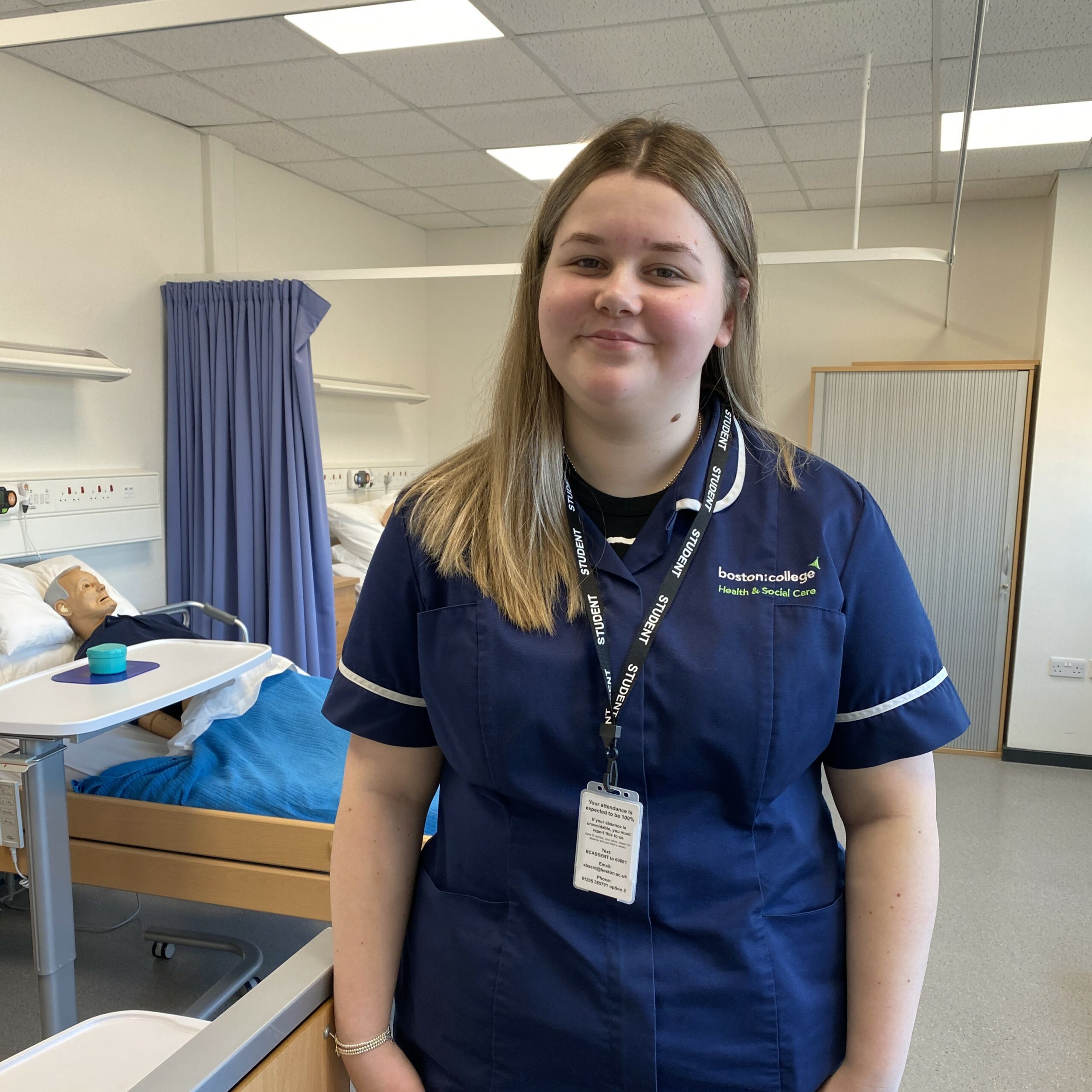 Health and Social Care learner Isabelle H-F standing smiling in the College's ward 