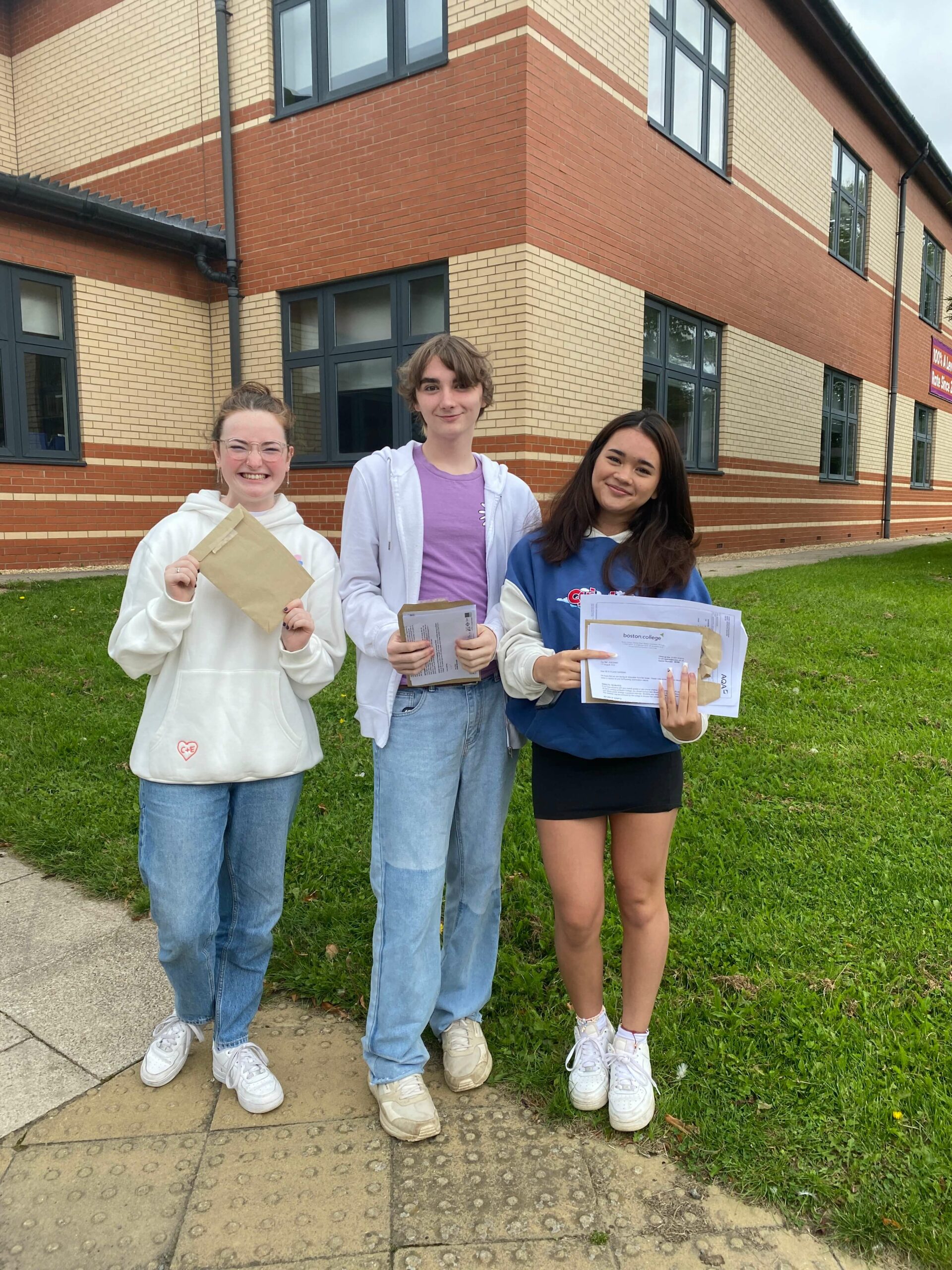 3 Boston College Learners posing with A-Level Results looking into camera