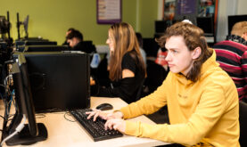 Boston College Business Learner, sat facing to the left, looking at a PC Screen whilst working