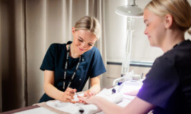 Boston College Beauty Therapy Learner applying nail varnish to a second learner