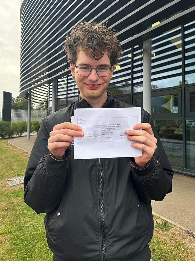Boston College Student Tristan smiling to the camera holding his GCSE Results