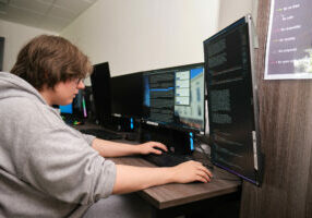 Boston College Digital Technologies student using a dual screen computer to code